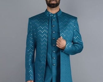 Puede incluir: Un traje de tres piezas de color turquesa con un abrigo largo estampado. El traje incluye un chaleco con botones y pantalones a juego. El abrigo tiene un patrón sutil y repetitivo. El conjunto se combina con zapatos de cuero marrón.
