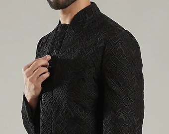 Puede incluir: Una chaqueta negra de manga larga con un patrón geométrico. La chaqueta tiene un cuello mandarín y un dobladillo largo y fluido.