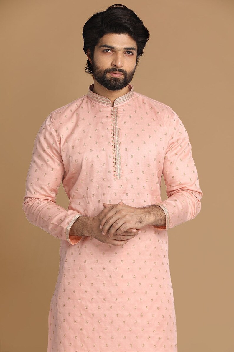 Op de afbeelding: Een roze langarmige kurta met een gouden geborduurd patroon. De kurta heeft een mandarijnkraag en een knoopsluiting.