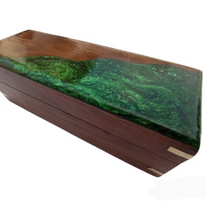 Può includere: Una scatola di legno con un intarsio in resina verde. La scatola ha un coperchio incernierato e dettagli in ottone.