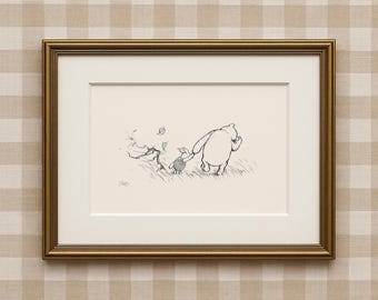 May include: A framed black and white illustration of Winnie the Pooh and Piglet walking together. The artwork is in a gold frame with a white mount. The background is a beige and white checked pattern.