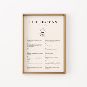 Pode incluir: Uma impressão emoldurada com moldura dourada com as palavras "LIFE LESSONS" e uma ilustração de Winnie the Pooh. A impressão inclui citações de Winnie the Pooh, em um fundo creme com texto preto.