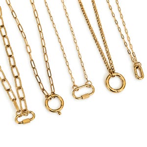 May include: A collection of five gold-toned metal chains of varying link styles. The chains feature different clasp mechanisms, including oval-shaped carabiner-style connectors and circular spring rings, arranged vertically against a plain background.