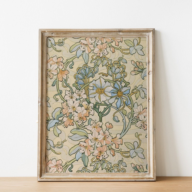 Puede incluir: Una impresi&oacute;n art&iacute;stica floral enmarcada con un fondo crema y un patr&oacute;n repetido de flores melocot&oacute;n, azules y verdes. La obra de arte est&aacute; encerrada en un marco de madera marr&oacute;n claro desgastado, lo que le da un aspecto vintage.