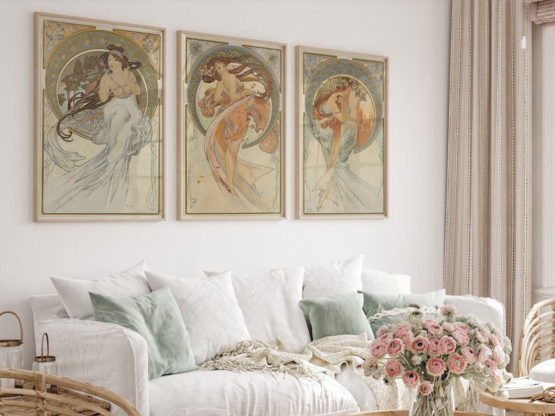 Puede incluir: Tres impresiones de arte enmarcadas que presentan ilustraciones de estilo Art Nouveau de mujeres con vestidos fluidos. Las impresiones est&aacute;n en una paleta de colores claros y vintage con acentos dorados.