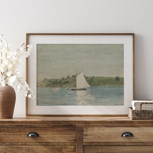 May include: A framed watercolor painting of a sailboat on a calm body of water with a small island in the background.
