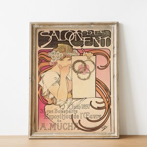 May include: A vintage poster advertising the Salon des Cent, an art exhibition in Paris, France. The poster features a woman in a white dress and a floral crown, holding a blank canvas. The text on the poster reads "Salon des Cent, Juin 1897, 31 rue Bonaparte, Exposition de l'&OElig;uvre de A. Mucha."