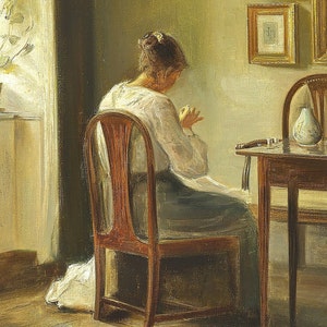 May include: A woman sits in a wooden chair, sewing in a sunlit room. The chair has a high back and a carved design. The woman is wearing a white blouse and a long skirt. There is a table with a vase and a glass on it in the background.
