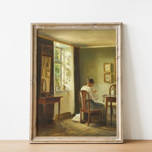 May include: A painting of a woman sitting at a table in a room with a window. The woman is wearing a white dress and is sewing. The room is decorated with a mirror and two framed pictures.