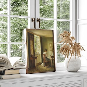 May include: A framed painting of a woman sitting at a table in a room with a window. The woman is wearing a light-colored dress and is sewing. The room is decorated with a mirror and a few other pieces of furniture.