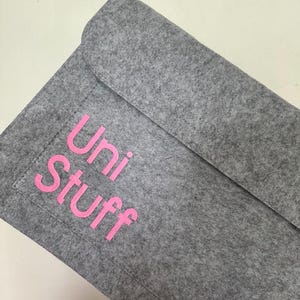 May include: Grey felt laptop sleeve with a pink "Uni Stuff" logo.