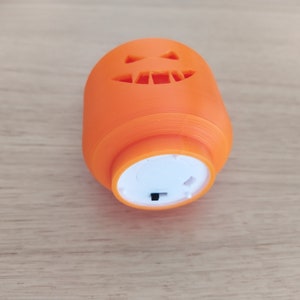 May include: An orange plastic jack-o'-lantern with a carved face and a white light-up base. The base has a small black switch.