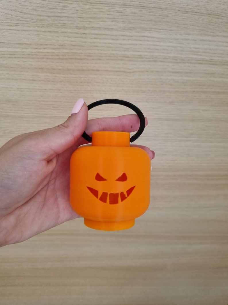 May include: Orange Halloween lantern with a black handle and a carved jack-o'-lantern face.