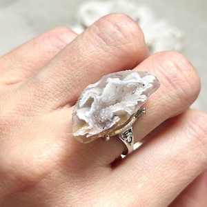 May include: A silver ring featuring a white agate stone. The agate has a natural, organic shape and a white, translucent appearance.