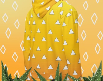 Puede incluir: Una sudadera con capucha amarilla con un patrón repetido de triángulos blancos. La sudadera tiene un diseño degradado, que pasa de amarillo a naranja. El fondo es naranja a juego con formas de diamantes blancos. La sudadera con capucha la lleva una persona.