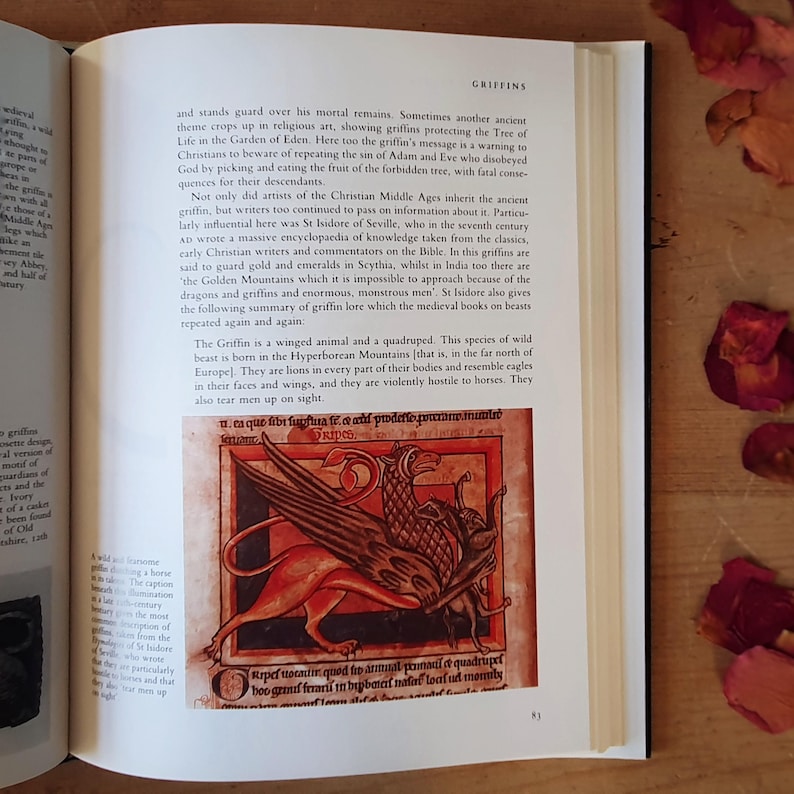 May include: An open book page with text and a detailed illustration of a griffin, a mythical creature with the body of a lion and the head and wings of an eagle. The illustration is in red, brown, and black.