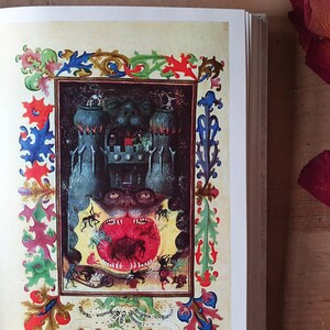 Może przedstawiać: Otwarta książka prezentuje średniowieczną ilustrację o mrocznym, fantastycznym motywie. Grafika przedstawia zamek, potworne postacie i żywą, ozdobną obw&oacute;dkę w kolorach czerwonym, niebieskim i zielonym. Obraz ma estetykę vintage.