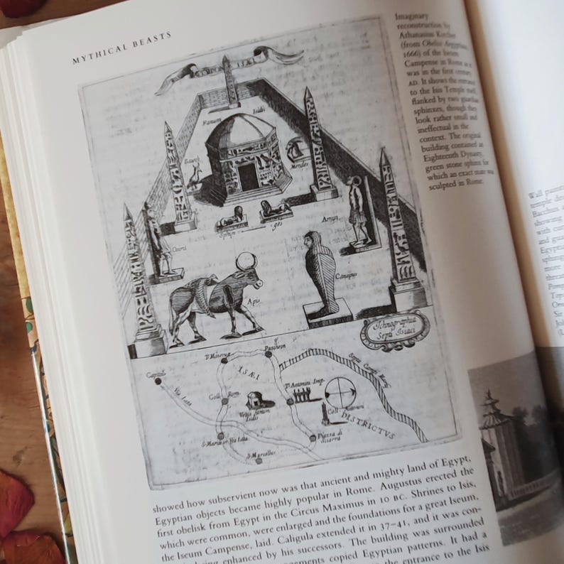 May include: An open book displays a detailed black and white illustration of ancient Egyptian structures and figures. The image includes obelisks, a temple, a cow, and a map, with the title "MYTHICAL BEASTS" at the top.