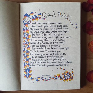 May include: An open book displaying a handwritten poem titled "Lover's Pledge." The calligraphy is framed by decorative blue, yellow, and orange floral designs. The author's name, Lynn New, is at the bottom of the page.