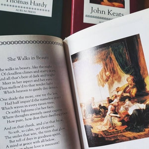 Puede incluir: Un libro con un poema de John Keats titulado "She Walks in Beauty". El poema est&aacute; impreso en una p&aacute;gina blanca con un borde negro. El libro est&aacute; abierto en el poema y se puede ver una pintura de un grupo de personas en una habitaci&oacute;n en la p&aacute;gina derecha.