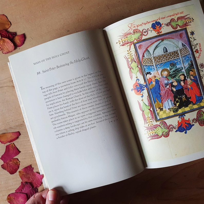 Może przedstawiać: Otwarta książka z tytułem "MASS OF THE HOLY GHOST" i kolorową ilustracją sceny religijnej. Obraz przedstawia postacie w szatach i dekoracyjną obw&oacute;dkę. Suche płatki r&oacute;ż są rozrzucone wok&oacute;ł książki.