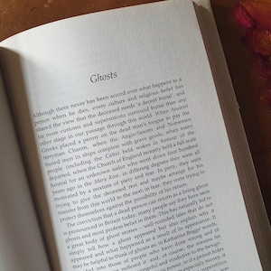 May include: Open book with the title "Ghosts" at the top of the page. The text discusses cultural beliefs about death, burial customs, and ghost stories.
