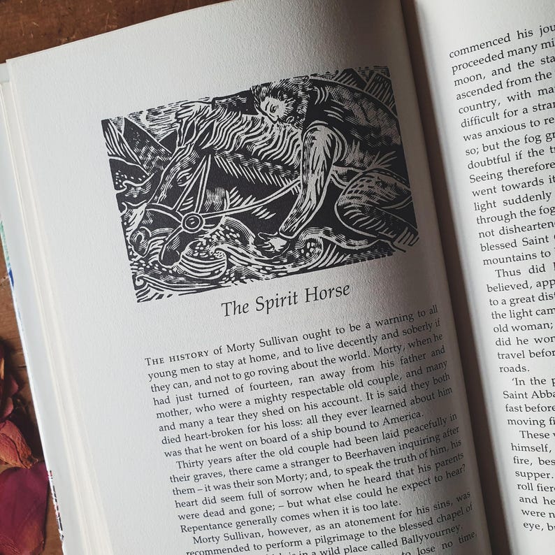 May include: A black and white illustration titled "The Spirit Horse" on a book page. The image depicts a person riding a horse, with text below describing the story. The book is open, with text on the adjacent page.
