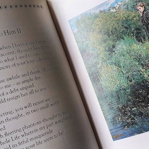 Puede incluir: Un libro con un poema titulado "She, to Him II" impreso en la p&aacute;gina izquierda. La p&aacute;gina derecha presenta una pintura de una mujer con un vestido negro de pie junto a un estanque en un bosque.