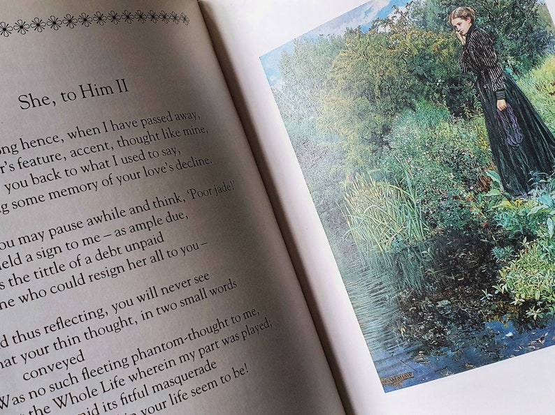 Puede incluir: Un libro con un poema titulado "She, to Him II" impreso en la p&aacute;gina izquierda. La p&aacute;gina derecha presenta una pintura de una mujer con un vestido negro de pie junto a un estanque en un bosque.