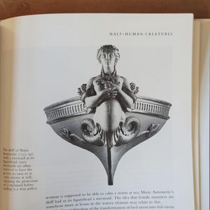 May include: A grayscale illustration from a book depicting a mermaid figurehead on a boat. The text "HALF-HUMAN CREATURES" is at the top. The mermaid has a human upper body and a fish tail, with decorative elements.