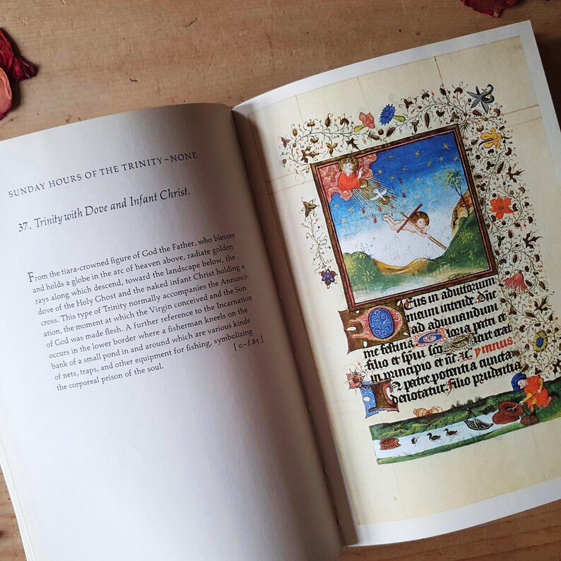 Może przedstawiać: Otwarta książka z szczeg&oacute;łową ilustracją religijną. Grafika przedstawia postacie z krzyżem, otoczone bogatymi kwiatowymi i liściastymi obramowaniami. Ilustracji towarzyszy tekst w języku łacińskim i angielskim.