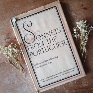 May include: A vintage hardback book titled Sonnets from the Portuguese by Elizabeth Barrett Browning, decorated by Valenti Angelo. The cream-coloured cover features black text, a decorative letter S, and a pink border, with worn edges and corners.