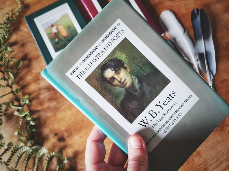 Puede incluir: Un libro azul turquesa con una cubierta blanca que presenta un retrato de W.B. Yeats. El t&iacute;tulo dice "The Illustrated Poets" y "W.B. Yeats The Last Romantic" con el logotipo de Aurum Press en la parte inferior.