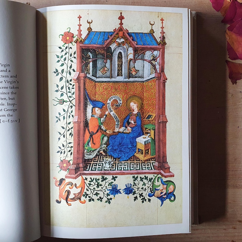 Może przedstawiać: Szczeg&oacute;łowa ilustracja z manuskryptu. Scena religijna przedstawia kobietę w niebieskiej szacie z aureolą, czytającą. Anioł w pomarańczowym i niebieskim prezentuje zw&oacute;j. Scena jest obramowana elementami architektonicznymi i kwiatowymi.