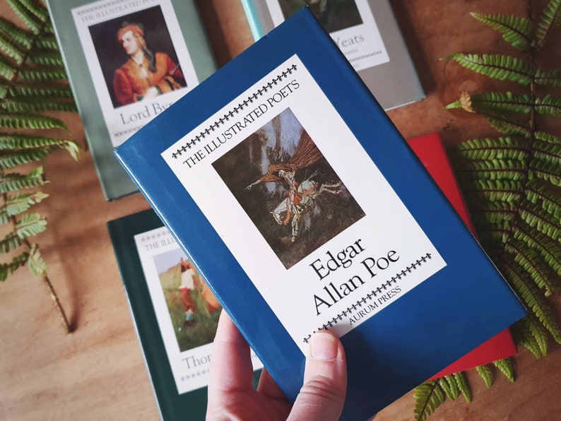 Puede incluir: Un libro de tapa dura azul titulado "The Illustrated Poets: Edgar Allan Poe" de Aurum Press. El libro presenta una ilustraci&oacute;n de una figura alada montando un caballo.
