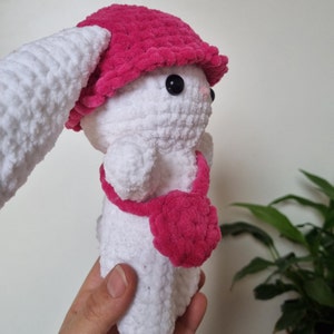 Lapin amigurumi au crochet en laine chenille blanc avec un chapeau rose et un sac rose de près de côté