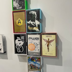 May include: A wall display of nine cassette tapes in colourful plastic cases. The tapes are titled "Bleach", "House of Pain", "In Utero", "Pwel", "Loop Nose Distrikt", and "Altern 8".