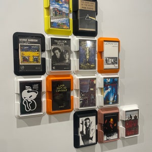 May include: A wall display of cassette tapes in various colored frames. The tapes include albums by Pink Floyd, George Harrison, Tears for Fears, Ultravox, and others.