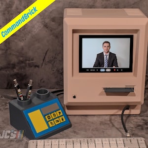May include: A beige retro-style computer with a screen displaying a person in a suit. A matching pen holder with a blue and yellow design sits to the left. The text "CommandBrick" is on a yellow banner.