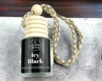 May include: A clear glass bottle with a black label that says "Lil Wax Bakery" and "Icy Black" with the website "www.sevyvn90.com". The bottle has a wooden cap with a gold and white braided string attached.