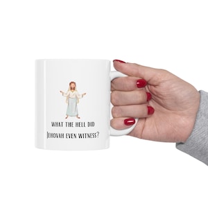 May include: White ceramic coffee mug with a cartoon illustration of Jesus and the text "What the hell did Jehovah even witness?"