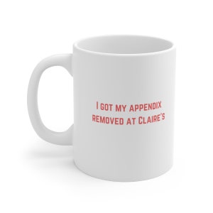 May include: White ceramic mug with the text "I got my appendix removed at Claire's" in red.