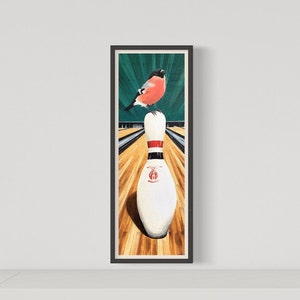 Könnte beinhalten: Gerahmtes Gemälde, das einen rot-schwarzen Vogel zeigt, der auf einer weißen Bowlingkegel mit roten Streifen sitzt. Der Hintergrund zeigt eine grüne und braune Bowlingbahn mit einer Holzspur. Das Kunstwerk ist in einem schwarzen Rahmen.