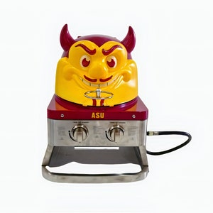 May include: A red and yellow gas grill with a cartoon devil head lid. The grill has two burners and a stainless steel base. The lid says "ASU" on the front.