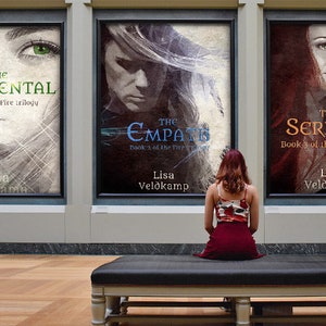 Op de afbeelding: Drie boekomslagen die in een galerie worden tentoongesteld. De omslagen tonen het gezicht van een vrouw met een dramatische achtergrond. De titels zijn "The Elemental", "The Empath" en "The Serpent". Elk boek maakt deel uit van een trilogie genaamd "The Fire Trilogy".