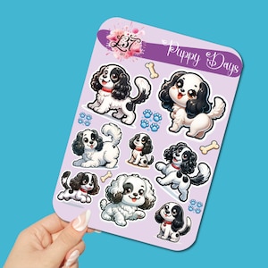 May include: A sheet of stickers featuring cartoon puppies in various poses. The puppies are primarily white with black markings and red collars. The stickers are on a lavender background with the words "Puppy Days" and paw prints.