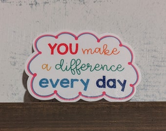 May include: A white cloud-shaped sign with a pink border and colorful text that reads "YOU make a difference every day".