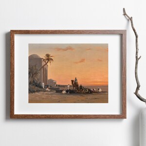 a framed picture of the artwork called Halt by the Well; by August Veillon. The image is of arab men and their camels in the desert next to a well and buildings.