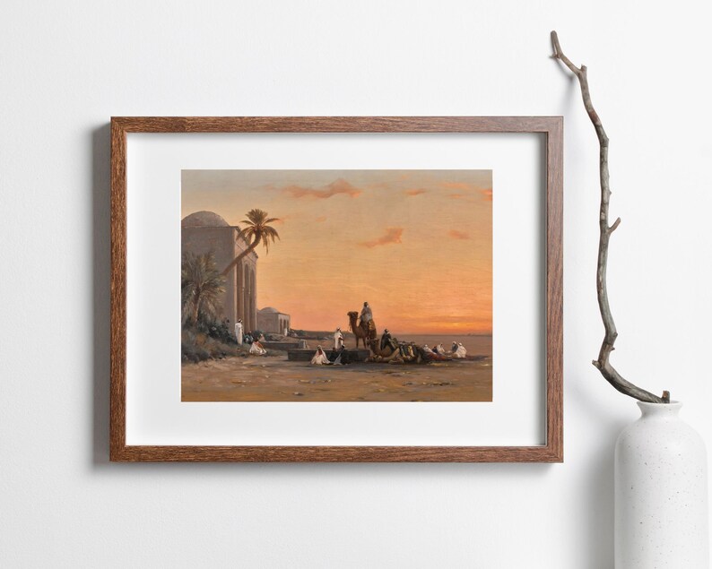 a framed picture of the artwork called Halt by the Well; by August Veillon. The image is of arab men and their camels in the desert next to a well and buildings.