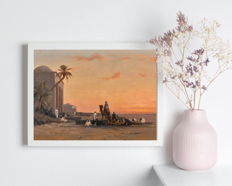 a framed picture of the artwork called Halt by the Well; by August Veillon. The image is of arab men and their camels in the desert next to a well and buildings.